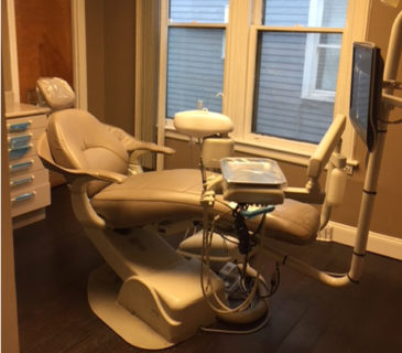 A modern dental chair in a warmly lit clinic room.