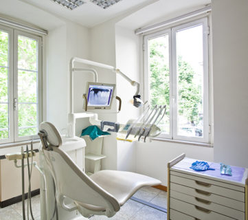 Bright dental clinic room with modern equipment and large windows.