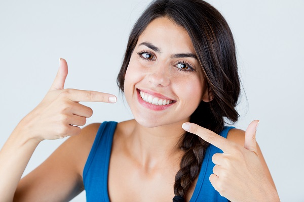 Smiling woman pointing at her teeth.