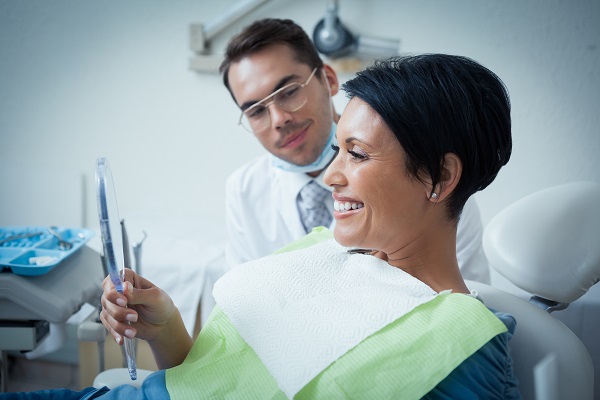 Patient smiling while holding dental mirror.